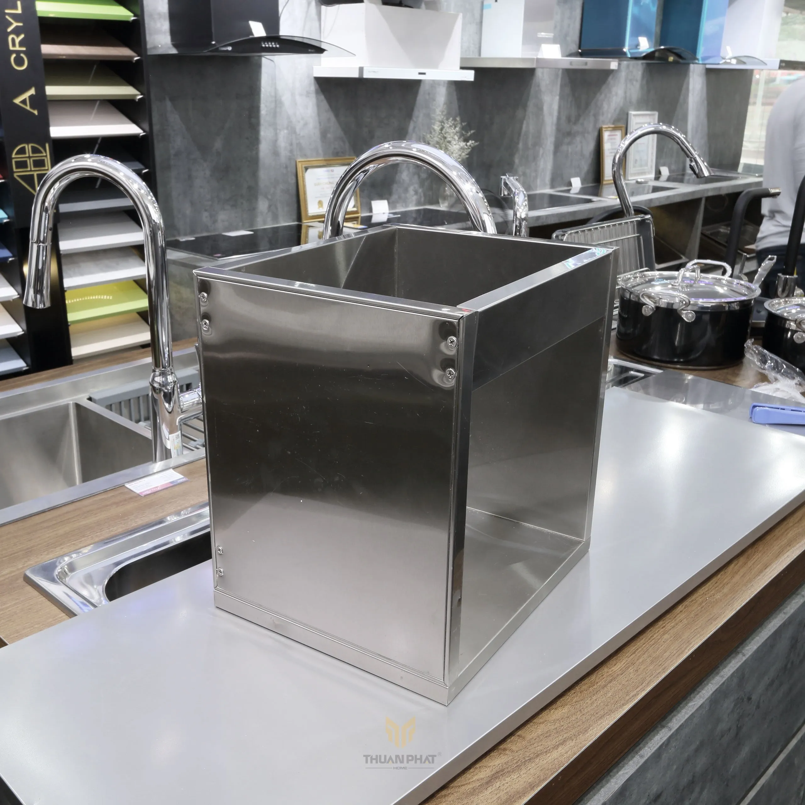 Tủ bếp inox cánh kính cường lực với màu hồng nhạt phía trên và vân gỗ phía dưới, đang được trưng bày tại Showroom Thuận Phát