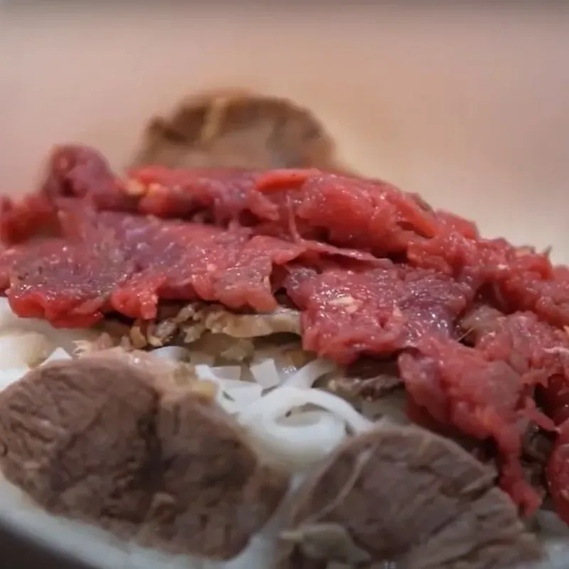 Tô phở bò Hà Nội hoàn chỉnh với bánh phở, thịt chín, thịt tái và rau thơm, chan nước dùng nóng hổi để thực khách thưởng thức hương vị trọn vẹn