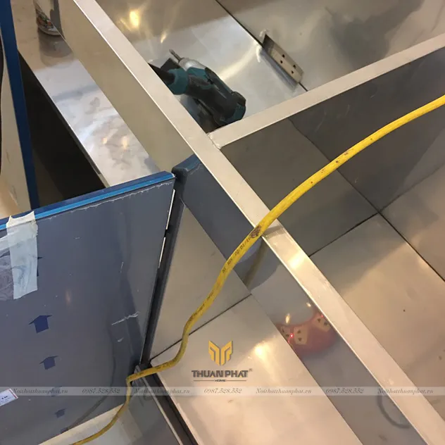 Cận cảnh khoang thùng tủ bếp inox cánh Acrylic còn nguyên tem và lớp bảo vệ của An Cường, đang được Thuận Phát lắp đặt tại nhà khách hàng